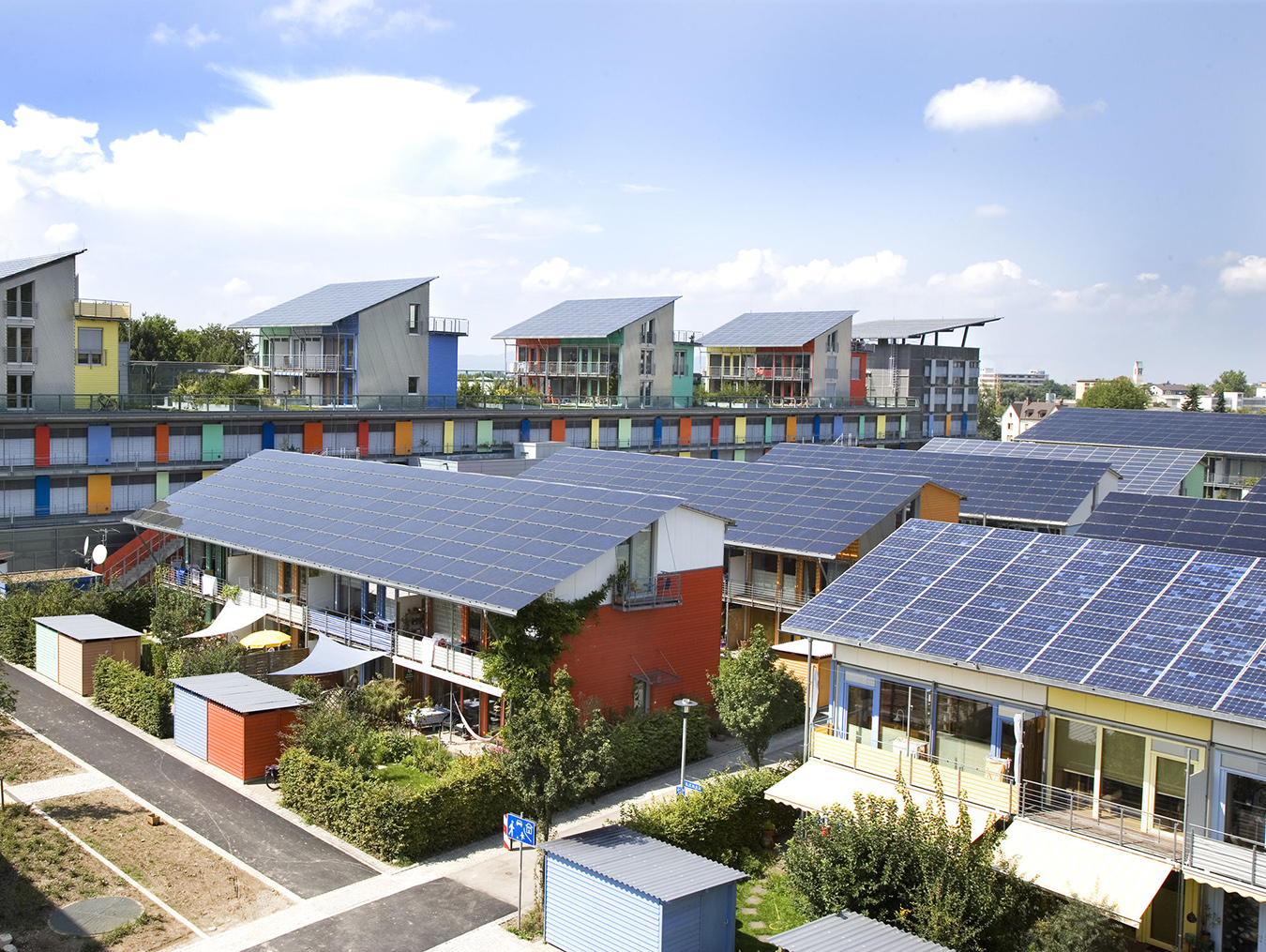 Rows of colorful houses, each with a slanted roof covered in solar panels.